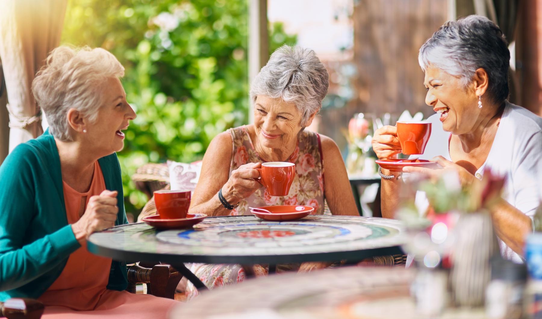 a group of women sitting at a table with cups of coffee